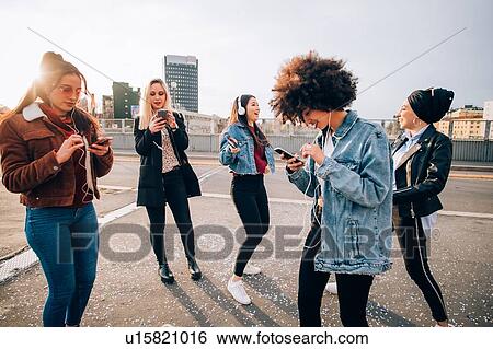 Stock Photograph - Friends dancing in street to smartphone music, Milan, Italy. Fotosearch