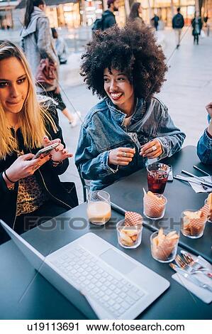 Stock Image - Friends having drinks at outdoor cafe, Milan, Italy. Fotosearch