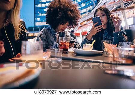 Stock Photo - Friends having drinks at outdoor cafe, Milan, Italy. Fotosearch