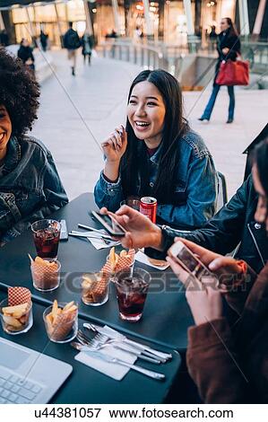 Stock Photo - Friends having drinks at outdoor cafe, Milan, Italy. Fotosearch
