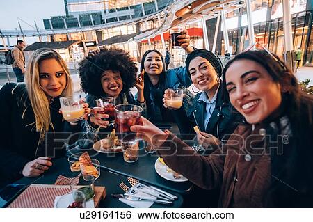 Stock Photograph - Friends having drinks at outdoor cafe, Milan, Italy. Fotosearch