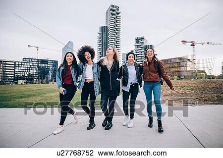 Stock Image - Friends laughing in street, Milan, Italy. Fotosearch