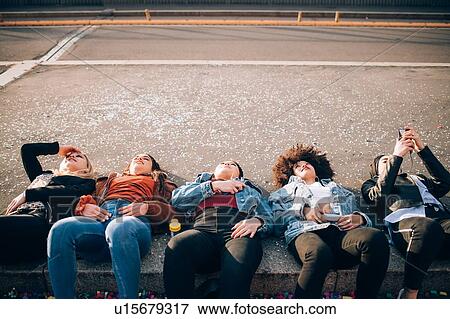 Friends lying on kerb, Milan, Italy View Large Photo Image Stock Photo - Friends lying on kerb, Milan, Italy. Fotosearch