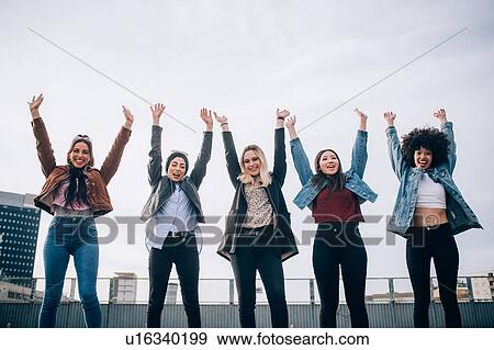 Stock Photo - Friends raising arms in triumph in street, Milan, Italy. Fotosearch
