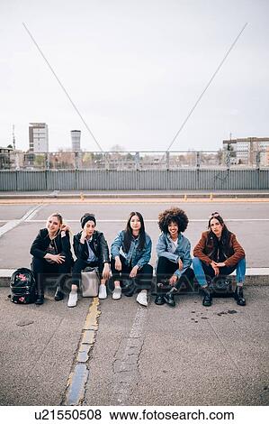 Stock Photo - Friends sitting on kerb, Milan, Italy. Fotosearch