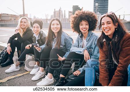 Friends sitting on kerb, Milan, Italy View Large Photo Image Stock Photography - Friends sitting on kerb, Milan, Italy. Fotosearch
