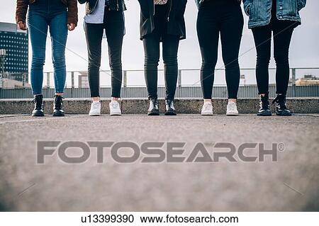 Stock Image - Friends standing side by side in street, Milan, Italy. Fotosearch