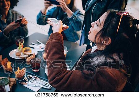 Friends taking photos of their food and drinks at outdoor cafe, Milan, Italy View Large Photo Image Stock Photo - Friends taking photos of their food and drinks at outdoor cafe, Milan, Italy. Fotosearch