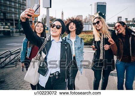 Stock Image - Friends taking selfie in street, Milan, Italy. Fotosearch