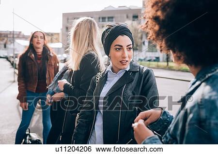 Stock Photograph - Friends talking in street, Milan, Italy. Fotosearch