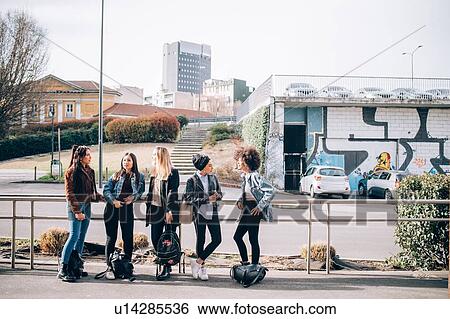 Stock Photograph - Friends talking in street, Milan, Italy. Fotosearch