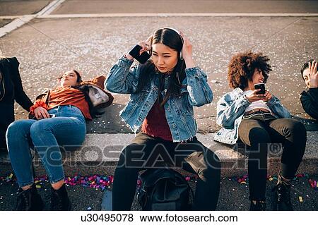 Stock Photo - Friends together on kerb, Milan, Italy. Fotosearch