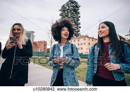 Stock Image - Friends walking in street, Milan, Italy. Fotosearch