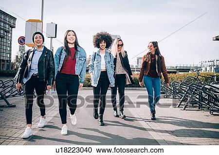 Stock Image - Friends walking in street, Milan, Italy. Fotosearch