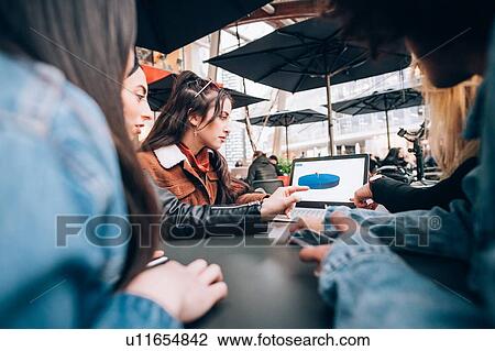 Stock Image - Friends working on project at outdoor cafe, Milan, Italy. Fotosearch
