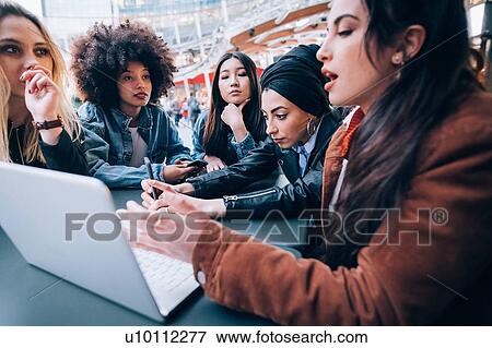 Stock Photo - Friends working on project at outdoor cafe, Milan, Italy. Fotosearch