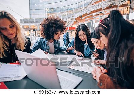 Stock Photo - Friends working on project at outdoor cafe, Milan, Italy. Fotosearch