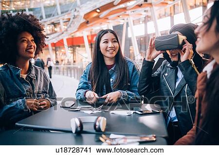 Stock Image - Friends working on virtual reality project at outdoor cafe, Milan, Italy. Fotosearch