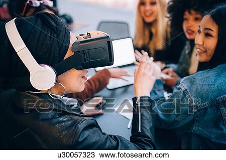 Stock Image - Friends working on virtual reality project at outdoor cafe, Milan, Italy. Fotosearch