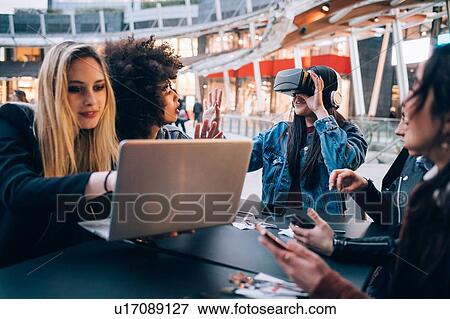 Stock Photo - Friends working on virtual reality project at outdoor cafe, Milan, Italy. Fotosearch