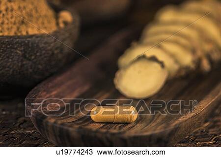 Stock Image - Ginger herbal supplement capsule and sliced ginger root. Fotosearch