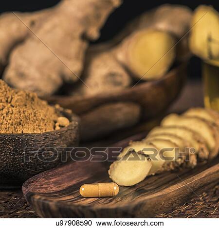 Stock Image - Ginger herbal supplement capsule and sliced ginger root. Fotosearch