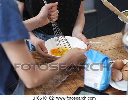 Girl and her sister baking a cake, whisking eggs in bowl on kitchen table, cropped view of hands View Large Photo Image Stock Image - Girl and her sister baking a cake, whisking eggs in bowl on kitchen table, cropped view of hands. Fotosearch