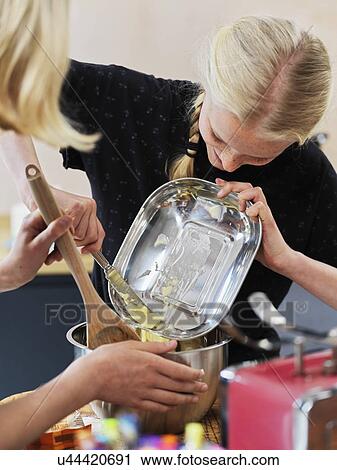 Girl and her sister baking a cake, scraping butter into mixing bowl on kitchen table, over shoulder view View Large Photo Image Stock Image - Girl and her sister baking a cake, scraping butter into mixing bowl on kitchen table, over shoulder view. Fotosearch