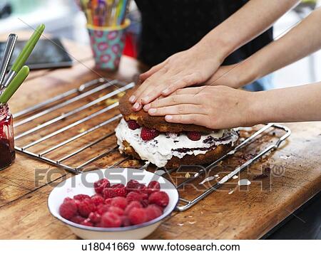 Girl and her sister baking a cake, pressing down top layer at kitchen table, cropped view of hands View Large Photo Image Stock Photo - Girl and her sister baking a cake, pressing down top layer at kitchen table, cropped view of hands. Fotosearch