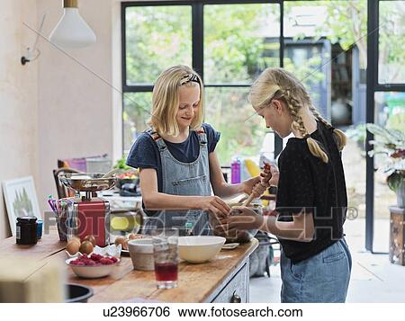 Girl and her sister baking a cake, stirring cake mixture in mixing bowl at kitchen table View Large Photo Image Stock Photograph - Girl and her sister baking a cake, stirring cake mixture in mixing bowl at kitchen table. Fotosearch