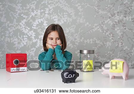 Stock Image - Girl looking at piggy banks. Fotosearch