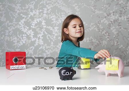 Stock Image - Girl putting money into piggy banks. Fotosearch