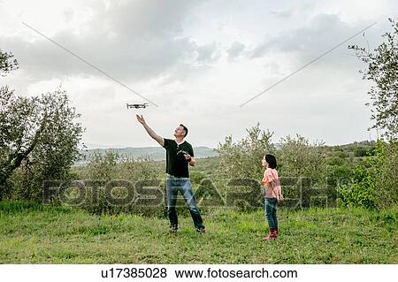 Girl watching father flying drone in scenic field landscape, Citta della Pieve, Umbria, Italy View Large Photo Image Stock Photo - Girl watching father flying drone in scenic field landscape, Citta della Pieve, Umbria, Italy. Fotosearch