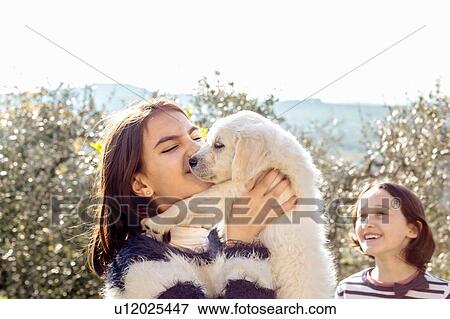 Girl with her friend holding up a cute golden retriever puppy in orchard, Scandicci, Tuscany, Italy View Large Photo Image Stock Photo - Girl with her friend holding up a cute golden retriever puppy in orchard, Scandicci, Tuscany, Italy. Fotosearch