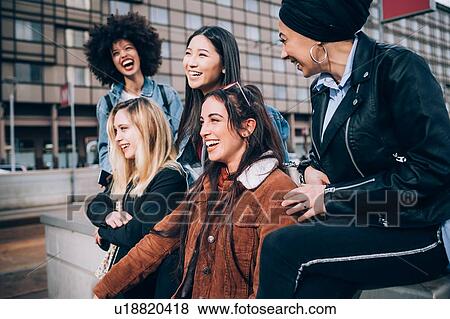 Stock Photo - Group of friends laughing in street, Milan, Italy. Fotosearch