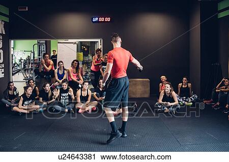 Stock Image - Group of women training in gym, listening to male trainer. Fotosearch