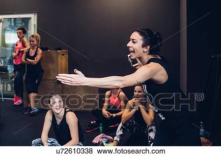Stock Photo - Group of women training in gym, laughing while taking a break. Fotosearch