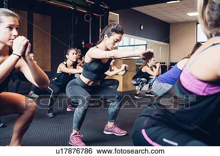 Stock Photograph - Group of women training in gym, squatting. Fotosearch