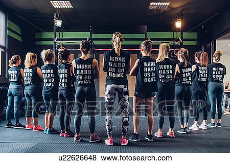Stock Photo - Group of women training in gym, wearing slogan t-shirts, rear view. Fotosearch