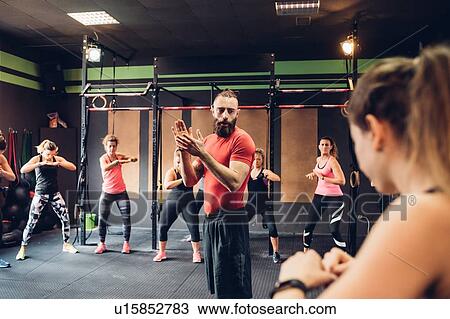 Group of women training in gym with male trainer View Large Photo Image Stock Image - Group of women training in gym with male trainer. Fotosearch