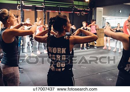 Stock Photo - Group of women training in gym, with arms raised. Fotosearch