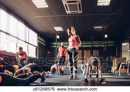 Group of women training in gym with male trainer, doing squats View Large Photo Image Stock Photo - Group of women training in gym with male trainer, doing squats. Fotosearch