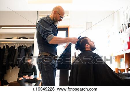 Hairdresser combing customer's hair in barber shop View Large Photo Image Stock Photograph - Hairdresser combing customer's hair in barber shop. Fotosearch