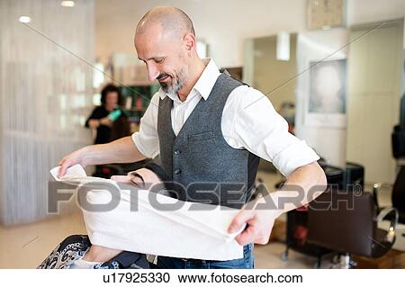 Stock Image - Hairdresser drying customer's face and hair with towel in barber shop. Fotosearch
