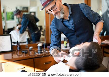 Hairdresser preparing to shave customer's beard in barber shop View Large Photo Image Stock Photography - Hairdresser preparing to shave customer's beard in barber shop. Fotosearch