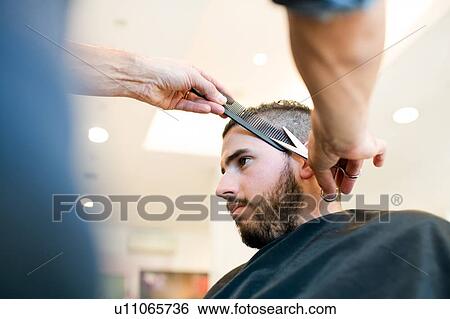Hairdresser trimming customer's hair in barber shop View Large Photo Image Stock Photograph - Hairdresser trimming customer's hair in barber shop. Fotosearch