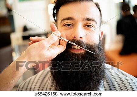 Stock Photo - Hairdresser trimming customer's moustache in barber shop. Fotosearch