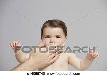 Stock Image - Hand over baby girl's mouth. Fotosearch