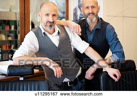 Stock Photo - Happy business partners in barber shop. Fotosearch