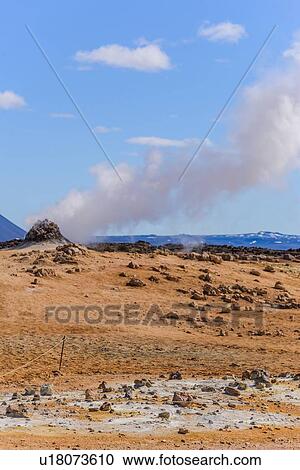 Stock Image - Hillside landscape with rock formation and rising steam against blue sky, Akureyri, Eyjafjardarsysla, Iceland. Fotosearch
